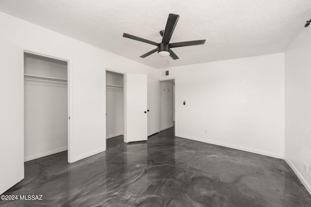 unfurnished bedroom featuring ceiling fan and multiple closets