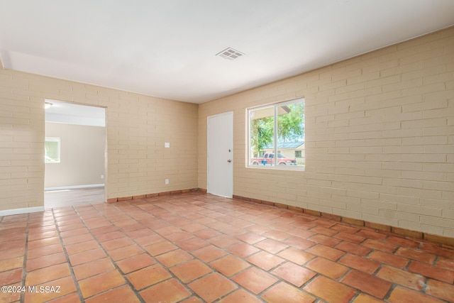 spare room with brick wall and tile patterned flooring