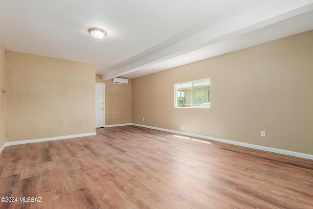 spare room with beam ceiling, a wall mounted AC, and wood-type flooring