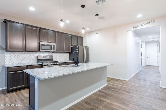 kitchen with a sink, visible vents, light wood-style floors, dark brown cabinets, and appliances with stainless steel finishes