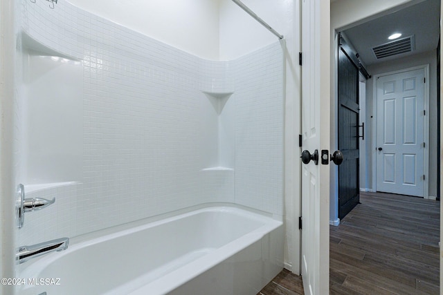 bathroom with visible vents, bathing tub / shower combination, and wood finished floors