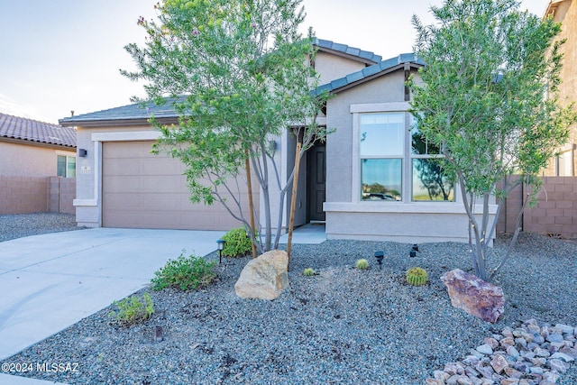 view of front of house featuring an attached garage, fence, concrete driveway, and stucco siding