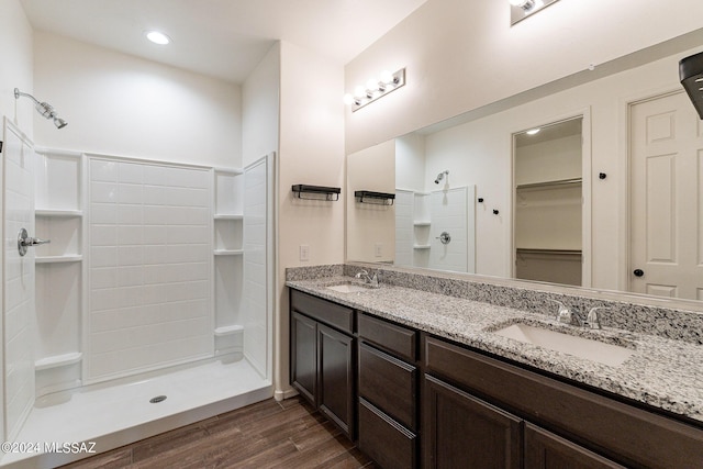 bathroom with a walk in closet, a sink, a shower stall, and wood finished floors