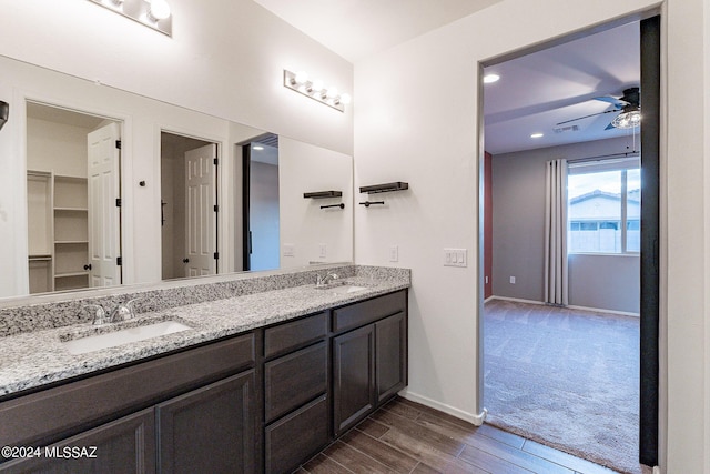 bathroom featuring a ceiling fan, a sink, baseboards, and double vanity