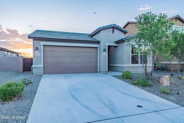 single story home with a garage, driveway, fence, and stucco siding