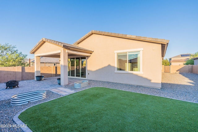 rear view of property featuring an outdoor fire pit, a patio area, a fenced backyard, and stucco siding