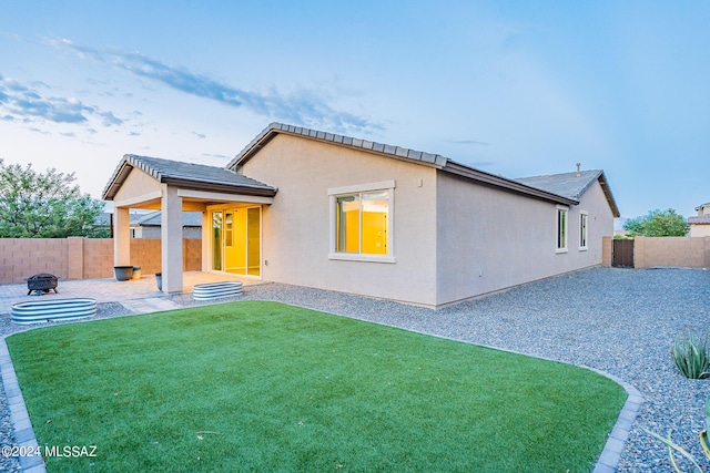 back of house featuring an outdoor fire pit, a patio area, a fenced backyard, and stucco siding