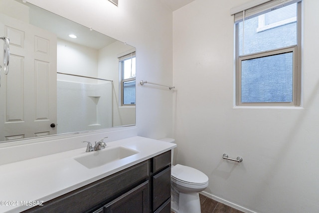 full bath featuring a shower, toilet, vanity, wood finished floors, and baseboards