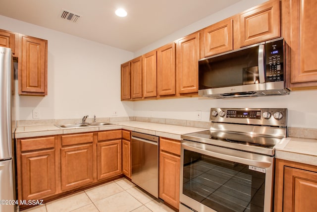 kitchen featuring light tile patterned flooring, appliances with stainless steel finishes, and sink