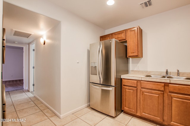 kitchen featuring sink, stainless steel fridge, and light tile patterned floors