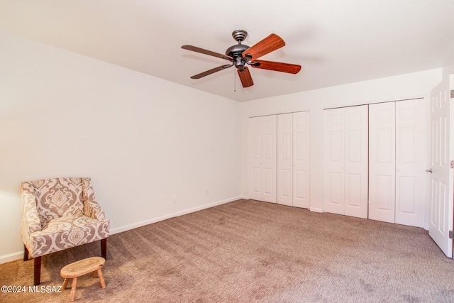 unfurnished bedroom with carpet floors, two closets, and ceiling fan