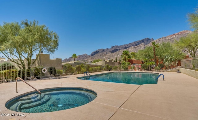 view of swimming pool with a patio, a mountain view, and a hot tub