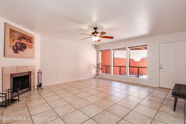 living room featuring ceiling fan, a tiled fireplace, and light tile patterned floors