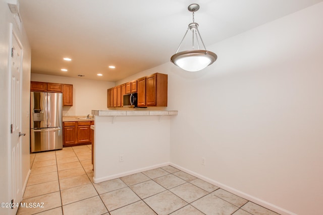 kitchen featuring appliances with stainless steel finishes, kitchen peninsula, pendant lighting, and light tile patterned flooring