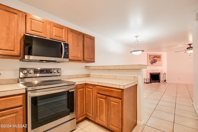 kitchen with ceiling fan, stainless steel appliances, light tile patterned floors, and pendant lighting