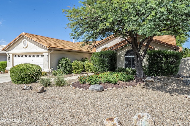 view of front facade featuring an attached garage, driveway, a tile roof, and stucco siding