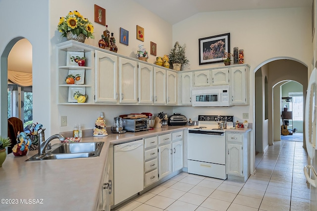 kitchen with white appliances, arched walkways, light countertops, open shelves, and a sink