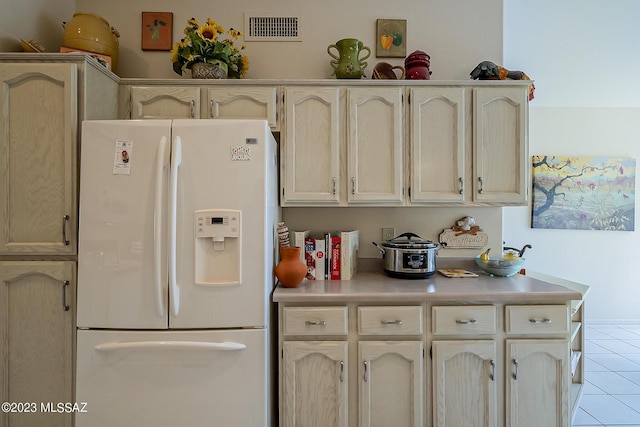 kitchen with light countertops, white refrigerator with ice dispenser, visible vents, and light tile patterned floors