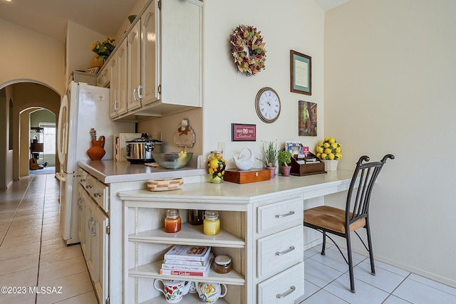 kitchen featuring arched walkways, light countertops, light tile patterned floors, and open shelves