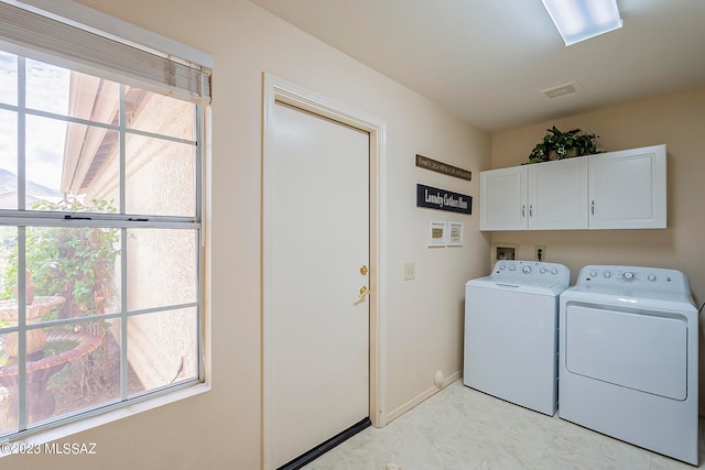 clothes washing area featuring plenty of natural light, cabinets, and washing machine and clothes dryer