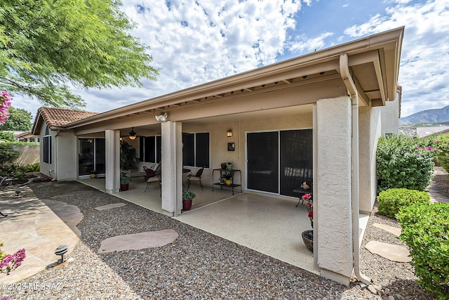 back of property with a patio area, ceiling fan, a tiled roof, and stucco siding