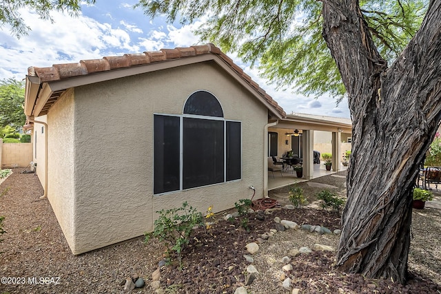 exterior space featuring a patio, fence, a ceiling fan, and stucco siding