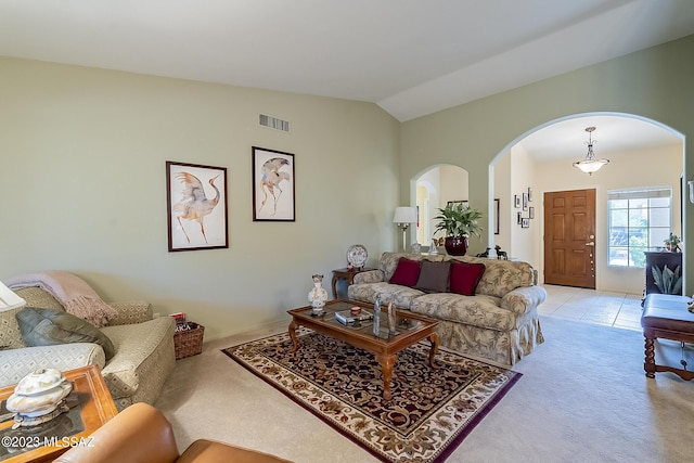 living room with visible vents, arched walkways, vaulted ceiling, and light colored carpet