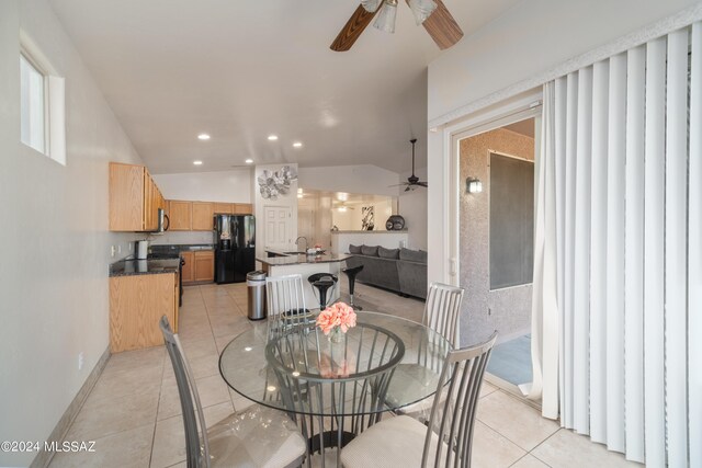 tiled dining area featuring lofted ceiling, ceiling fan, and sink