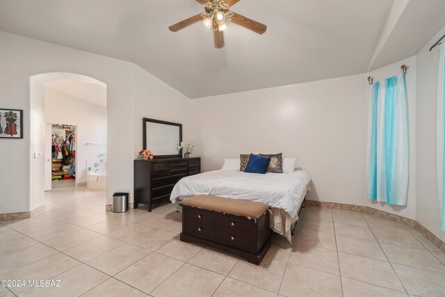 bedroom featuring ceiling fan, light tile patterned floors, vaulted ceiling, and a walk in closet