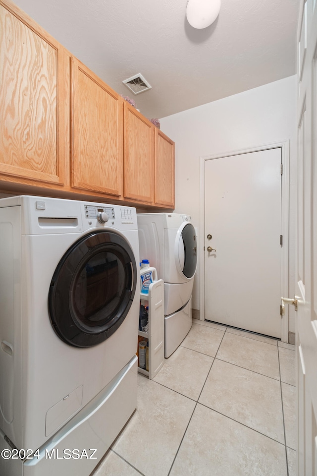 washroom with light tile patterned floors, cabinets, and independent washer and dryer