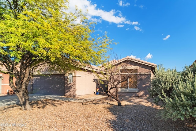 exterior space with a garage, driveway, a tiled roof, and stucco siding