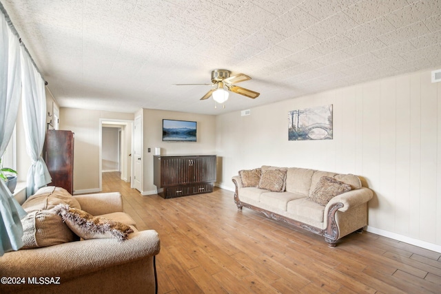 living room featuring hardwood / wood-style floors, a ceiling fan, baseboards, and visible vents