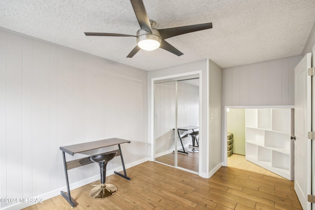 interior space featuring a ceiling fan, a closet, baseboards, and wood-type flooring