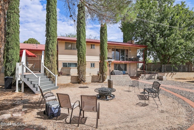 rear view of house featuring a fire pit, stairway, fence, metal roof, and a patio
