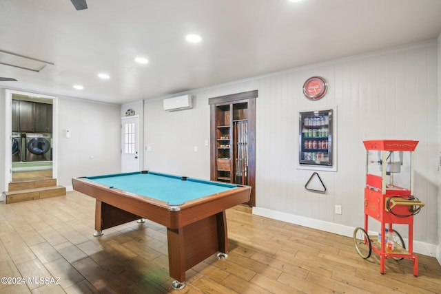 playroom featuring pool table, a wall unit AC, wood finished floors, washing machine and clothes dryer, and baseboards