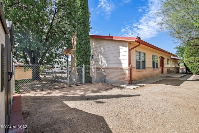 view of home's exterior featuring a patio, brick siding, fence, and a gate
