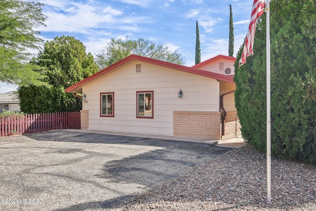 view of side of home featuring brick siding and fence