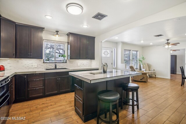 kitchen with light wood finished floors, a breakfast bar area, decorative backsplash, and a sink