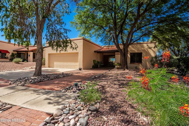 view of front of house featuring a garage, driveway, a tiled roof, and stucco siding