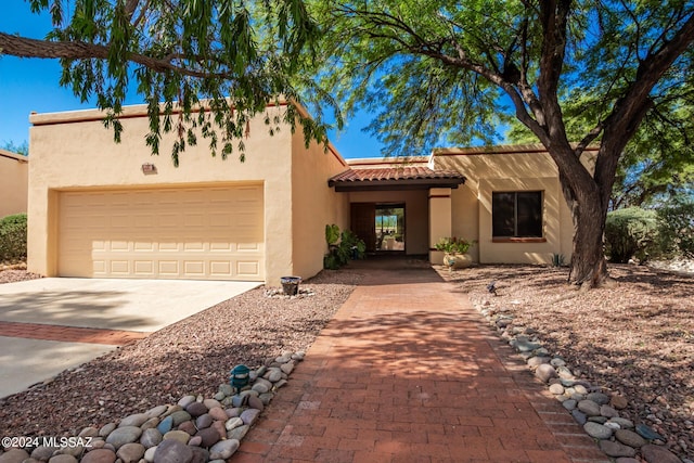 view of front facade featuring a garage, a tile roof, concrete driveway, and stucco siding