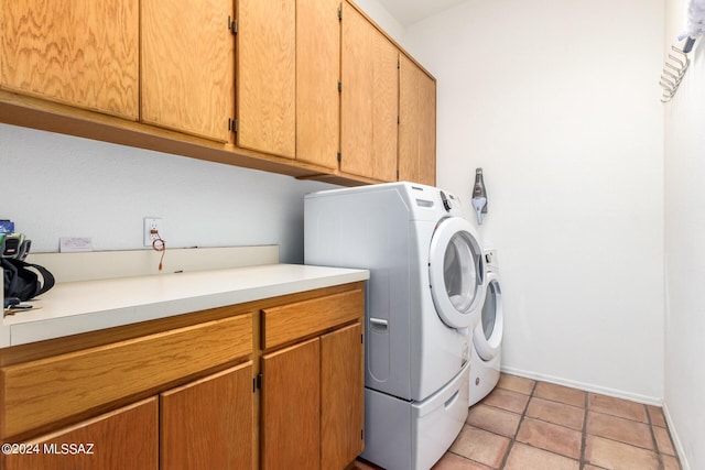 clothes washing area with washing machine and dryer, cabinet space, baseboards, and light tile patterned flooring