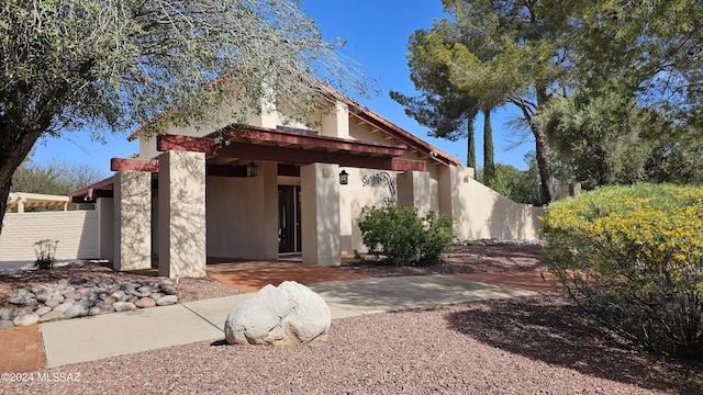 view of front facade featuring fence and stucco siding