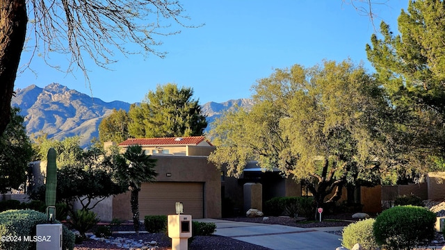 view of front of house featuring a tile roof, a mountain view, concrete driveway, and stucco siding