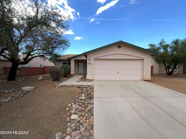 ranch-style home with an attached garage, driveway, fence, and stucco siding