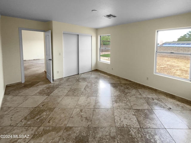 unfurnished bedroom with a closet, visible vents, and baseboards