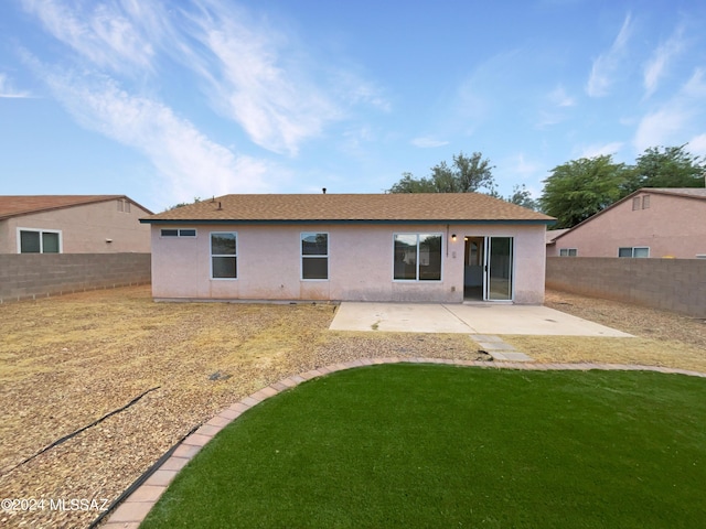 rear view of property with a yard, a fenced backyard, a patio, and stucco siding