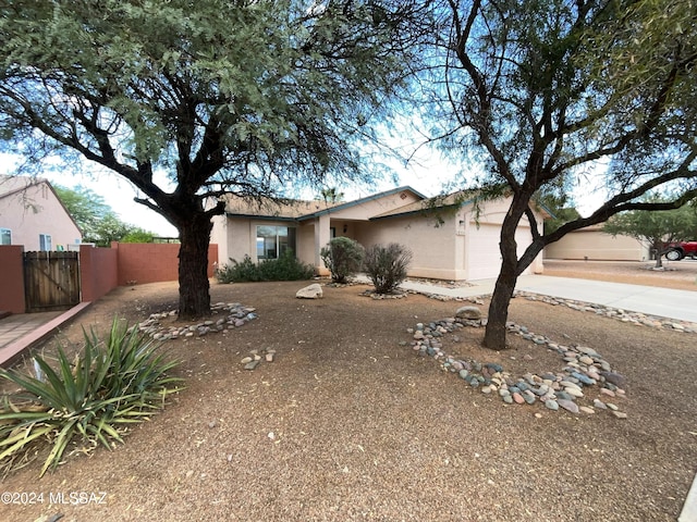 ranch-style home with concrete driveway, fence, an attached garage, and stucco siding