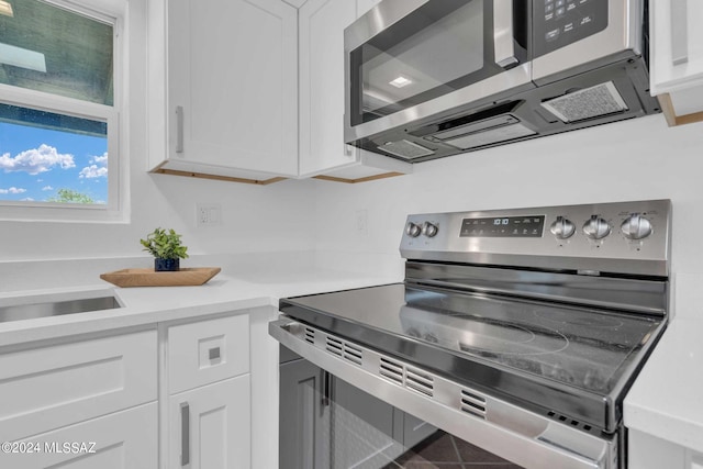 kitchen with white cabinetry, light countertops, a sink, and stainless steel appliances