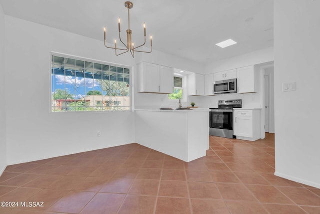 kitchen with tile patterned floors, white cabinetry, appliances with stainless steel finishes, a peninsula, and light countertops