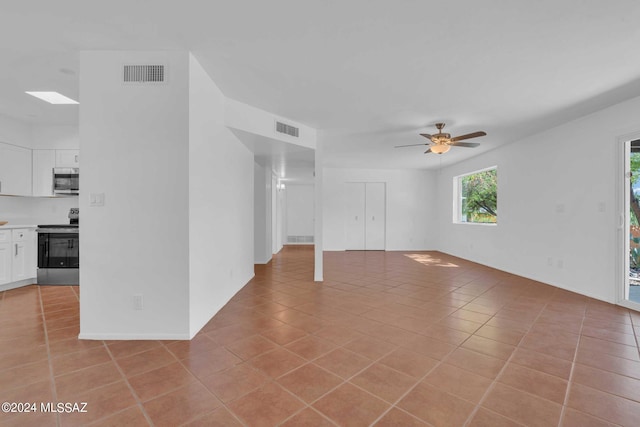 unfurnished room featuring light tile patterned floors, visible vents, a skylight, and a ceiling fan